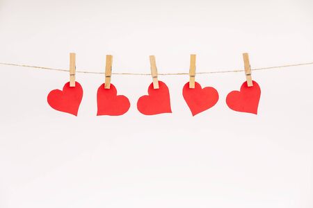 Clothes pegs and red paper hearts on rope isolated on white background. Valentines day conceptの写真素材