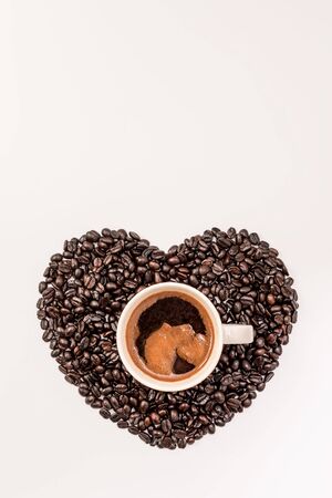 Top view of tasty coffee in cup or mug with heart made of coffee grains on white backgroundの写真素材