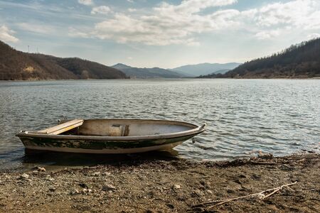 Boat on lake against mountains. Fishing boat on a still lake and mountains in background. Fishing boatの写真素材