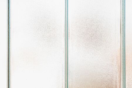 Old frosted patterned glass on a tiled window. Texture, transparent, matte white and grey frosted glass, blur effect. Stained glass decorative backgroundの写真素材