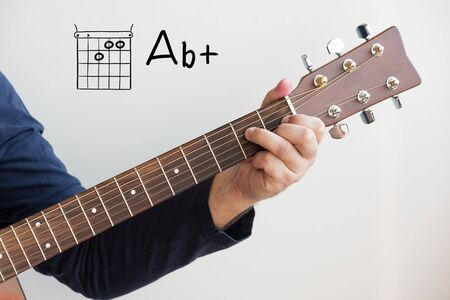 Learn Guitar - Man in a dark blue shirt playing guitar chords displayed on whiteboard, Chord A flat+ (Ab+)の写真素材