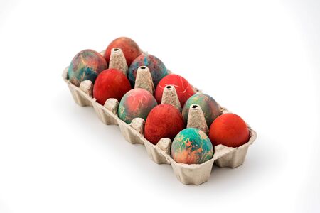 Colorful Easter eggs in cardboard egg box on white background. Raw chicken eggs in open egg box on a...