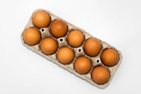 Chicken eggs in cardboard egg box on white background. Raw chicken eggs in open egg box on a white...