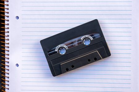 Black Plastic cassette tape on a notebook paper. Vintage concept with old cassette tapeの写真素材