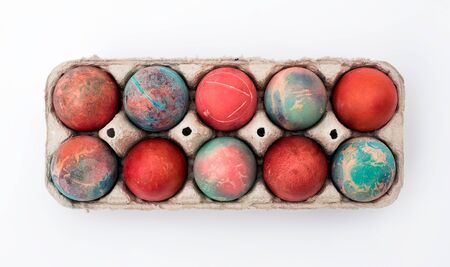 Colorful Easter eggs in cardboard egg box on white background. Raw chicken eggs in open egg box on a white background. Eggs in the package.の写真素材