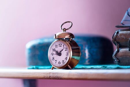Vintage alarm clock on a shelf lit by morning sun rays. Vintage background items.の写真素材