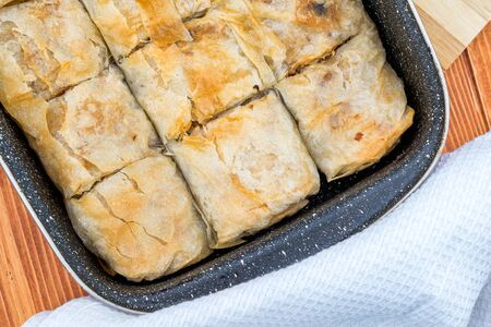 Apple pie homemade strudel in a baking iron plate on a wooden table just out of the oven. Pie with apples, raisins and cinnamon, sweet pastriesの写真素材
