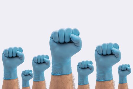 Fists Hands in medical blue latex protective gloves as a sign of resistance to pandemic - on white background stop disease signの写真素材