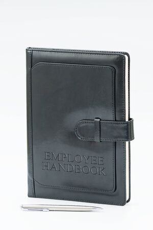 Black Leather Employee Handbook or manual with a pen on a white background - personnel management policy, explains business goals, results, defines personnel practicesの写真素材