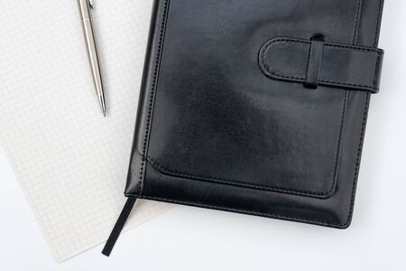 Black leather notebook and a pen on white background. Businessman workspace or diary. Business planning and work day organizationの写真素材