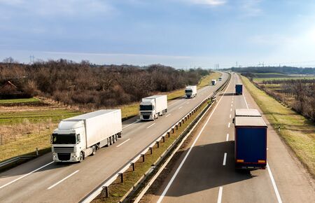 Highway transportation with a convoy of Lorry trucks passing trucks under a beautiful sunset skyの写真素材