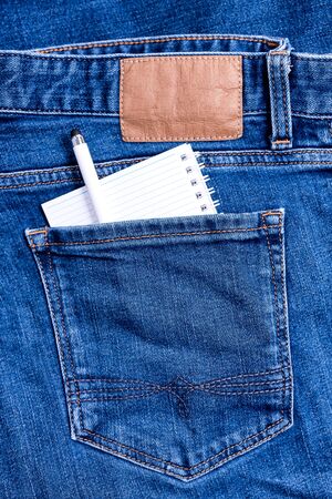 Close up of Jeans back pocket of classic blue denim pants with small notebook and a pen.の写真素材
