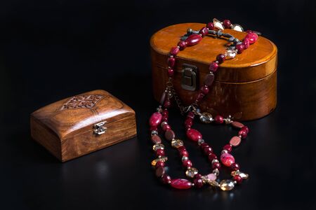 Two Old wooden jewelry caskets and a glass bead necklace isolated on black background. Wooden   boxes for different decorations or small trifles.の写真素材