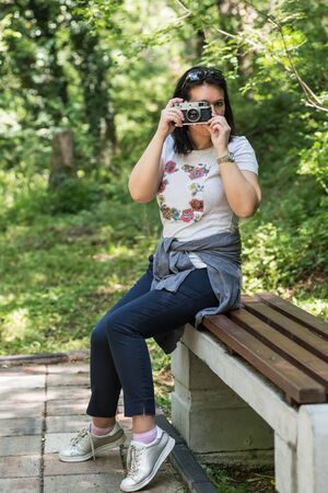 Woman taking photo at park outdoor with copy space. Beautiful woman tourist photographer with vintage camera. lady photographer, female Portrait.の写真素材
