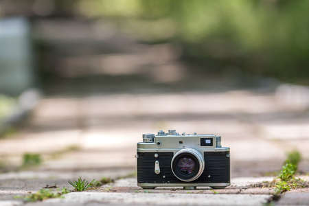 Spring time mood still life: vintage rangefinder camera laying on pavement with leaves of grass...