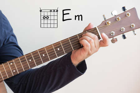 Learn Guitar - Man in a dark blue shirt playing guitar chords displayed on whiteboard, Chord E minorの写真素材