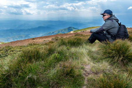 Man with backpack at a Mountain top. Mountain landscape view. Mountain layers landscape. Meadows and mountains landscape. Blue mountains layers landscape. Top of the Mountainsの写真素材