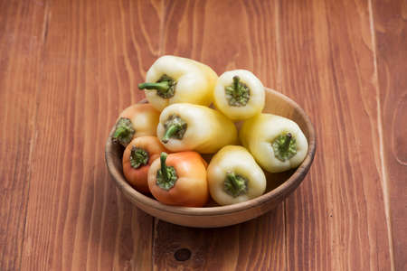 Fresh raw peppers in a wooden bowl. Ripe orange-red peppers. Close up. Copy space.の写真素材