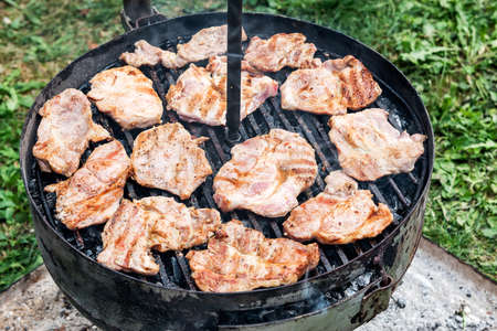Kettle Charcoal BBQ Barbecue Grill in garden or backyard. Side View of Black Kettle Grill in home front or backyard and green lawn. Portable BBQ Grill for Outdoor Grill Cookingの写真素材