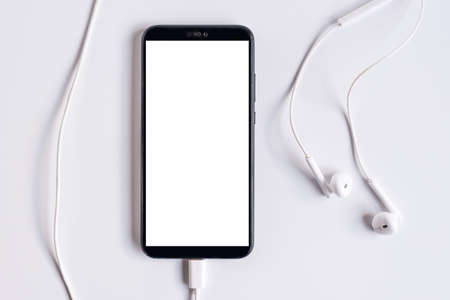 Smartphone with earphones on white background. Close-up of smart phone with headphones on a white background. Listen to musicの写真素材