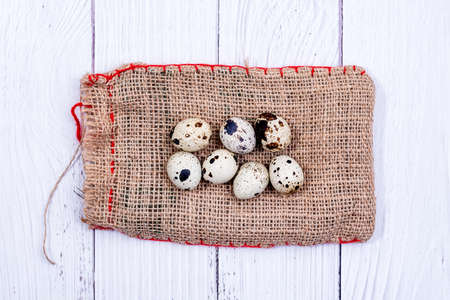 Quail eggs on burlap cloth bag. Group of quail eggs close-up. Top view. Detailed closeup of spotted quail eggsの写真素材