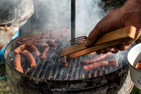 Kettle Charcoal BBQ Barbecue Grill in garden or backyard. Sausages on grill with a lot of smoke....