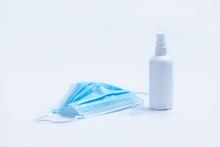 Blue Surgical protective mask and Alcohol Disinfectant spray bottle on white background.の写真素材