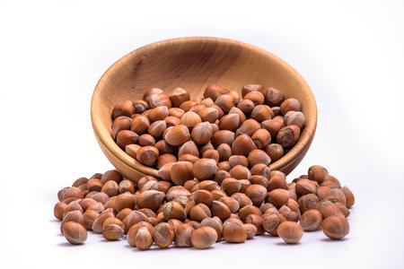 Hazelnuts spilled from wooden bowl on white background. Solid ripe Hazelnutsの写真素材