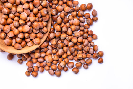 Hazelnuts spilled from wooden bowl on white background. Solid ripe Hazelnutsの写真素材