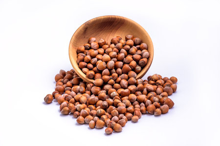 Hazelnuts spilled from wooden bowl on white background. Solid ripe Hazelnutsの写真素材