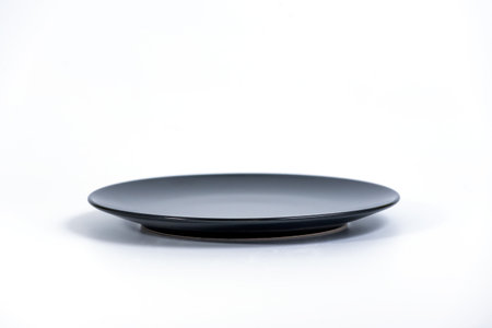 Empty Black plate isolated on white background side view, selective focusの写真素材