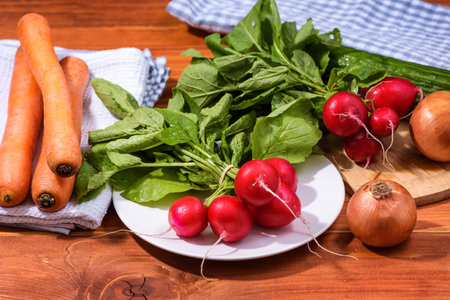 Fresh red radishes on wooden table with other vegetables. Growing organic vegetables. Large bunch of raw fresh juicy garden radish with onions, carrots and cucumberの写真素材