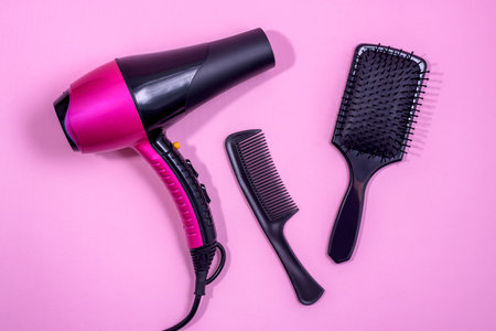 Hair dryer, Comb and hair brush on a pink background. Professional hairdresser set. Tools necessary for hair care.の写真素材