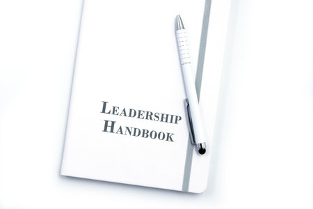 White Leadership Handbook or manual with White pen on white table surface - personnel management policy, explains business goals, results, defines Leadership practicesの写真素材