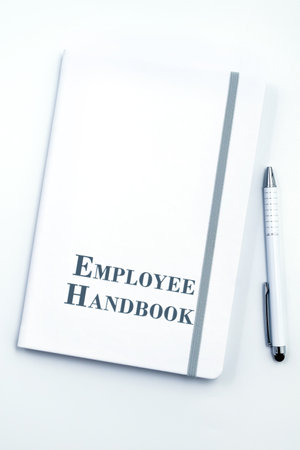 White Employee Handbook or manual with White pen on white table surface - personnel management policy, explains business goals, results, defines Leadership practicesの写真素材