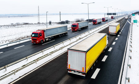 Highway transportation with a convoy of Lorry trucks passing trucks in a snowy winter landscapeの写真素材