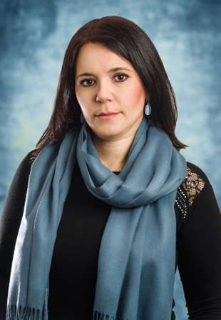 Serious Middle age caucasian business woman wearing black blouse and blue scarf relaxed with serious expression on face. simple and natural looking at the camera portraitの写真素材