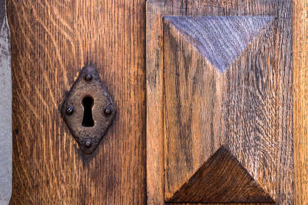Close-up view of an ancient door key lock on an old wooden door