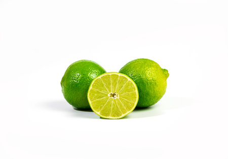 Two whole limes and slice of lime fruit isolated on white backgroundの写真素材