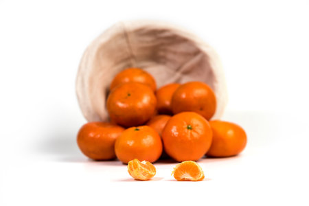 Ripe juicy tangerines spilling from a basket, Fresh fragrant mandarins, isolated on white bacground, selective focusの写真素材