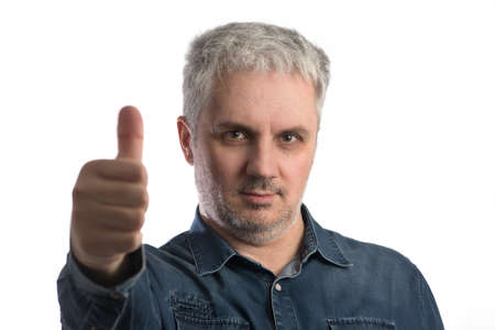 Middle age man in blue jeans shirt giving the thumbs-up sign looking at camera - isolated on white background with clipping path includedの写真素材