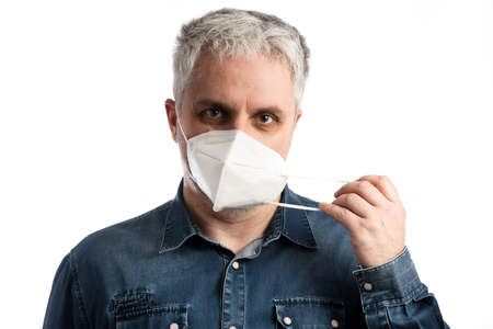Middle age man in blue jeans shirt puts on a face mask - isolated on white background