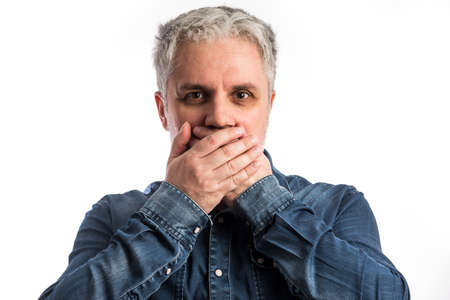 Middle age man in blue jeans shirt playing speak no evil - isolated on white background with...
