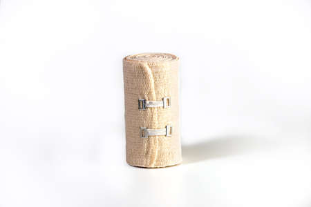 Woven elastic medical bandage rolled into roll and fixation clips. Compression Bandage on a white...