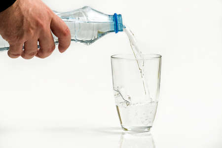 Water bottle pour water to glass on white backgroundの写真素材