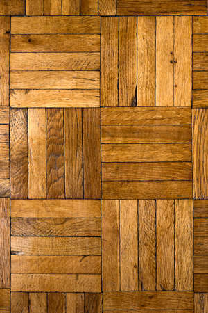 Old wooden worn parquet close-up, background with cracks and scratches, made of small brown boards. Texture and patternの写真素材