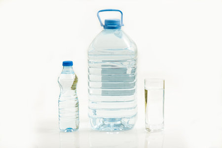 Bottled water isolated over a white background - Large, small bottle and a glass of waterの写真素材