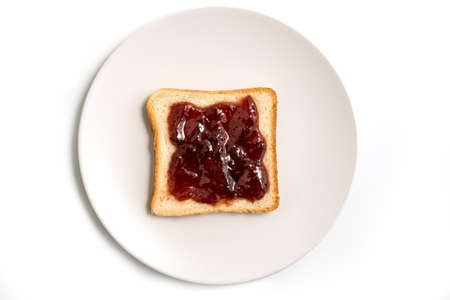 Slice of toasted bread with red strawberry jam in a white plate isolated on white background - top...
