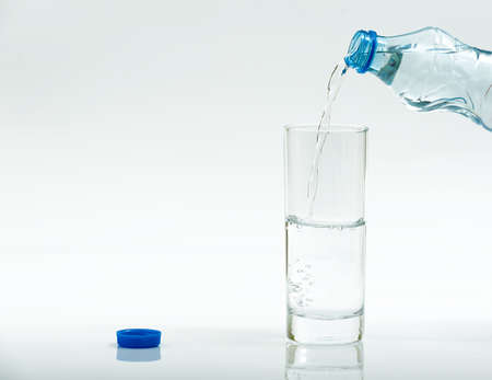 Water bottle pour water to glass on white backgroundの写真素材