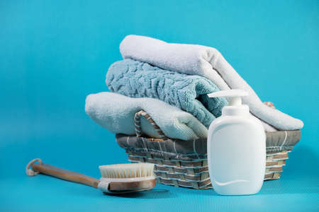 Bathroom Set on blue background - liquid soap, brush and towels in a wicker basketの写真素材